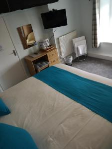 a bedroom with a bed with a blue and white blanket at Y Giler Arms in Pentrefoelas