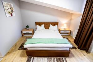 um quarto com uma cama e duas mesas de cabeceira em Casa Blum em Lugoj