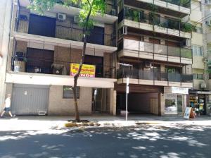 una mujer caminando por una calle en frente de un edificio en Confortable dpto ,100 m2, cochera en el edificio gratis , balcon grande a la calle, cerca MOVISTAR ARENA en Buenos Aires