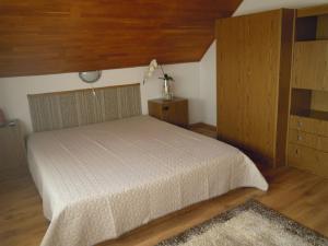 1 dormitorio con cama blanca y techo de madera en Thomas vendégház, en Vonyarcvashegy