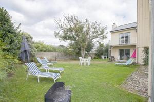 a yard with chairs and tables and a house at Les Costils in Saint-Laurent-sur-Mer