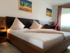 a bed with white sheets and pillows in a room at Hotel Europa in Ramstein-Miesenbach