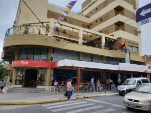 a woman crossing a street in front of a building at HOTEL CONTINENTAL COSQUIN in Cosquín