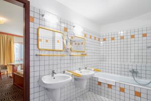 a bathroom with two sinks and a bath tub at Sándor Hotel in Pécs