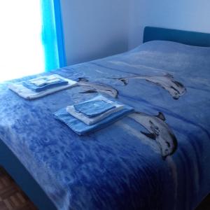 Una cama con colcha azul con ropa. en Rio de Mouro Quartos en Sintra