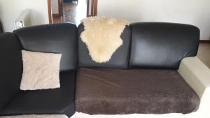 a black leather couch with a furry pillow on it at Rio de Mouro Quartos in Sintra