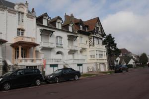 dos coches estacionados frente a un gran edificio blanco en SPLENDIDE T3 DE 70m2 VUE MER A 2 MINUTES DU CENTRE-VILLE, en Le Touquet-Paris-Plage