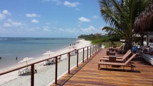 a wooden boardwalk on a beach with chairs and umbrellas at Marupiara Suites Flats in Porto De Galinhas