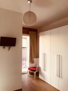 een woonkamer met witte kasten en een rode stoel bij B&B Ebo' in Olbia