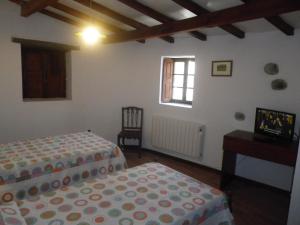 a bedroom with two beds and a television in it at Casa da Bica Gondesende in Bragança