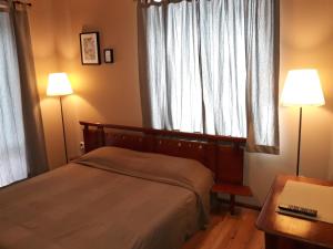 ein Schlafzimmer mit einem Bett, zwei Lampen und einem Fenster in der Unterkunft Family Hotel Pchelina in Kloster Rila