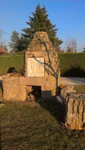 a stone oven sitting in the grass with a tree at Chambre de la baronne de Rochegrosse in Saint-Maurice-en-Gourgois