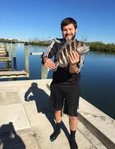 un homme tenant un poisson dans la main dans l'établissement Belleview Gulf Condos, à Clearwater Beach
