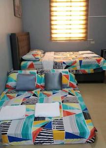 two twin beds in a bedroom with a colorful quilt at Lucena Meg's Studio Apmnt VIP rm-Near SM-Wifi in Ilayang Dupay