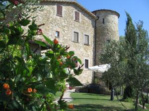 duży kamienny budynek z wieżą na górze w obiekcie Agriturismo Castello Di San Vittorino w mieście Gubbio