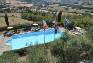 a swimming pool with chairs and umbrellas and flags at Agriturismo Castello Di San Vittorino in Gubbio