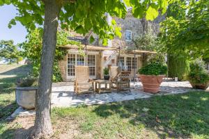 un patio con sillas y una mesa frente a una casa en Les Hiboux du Domaine du Moulin, en Étables