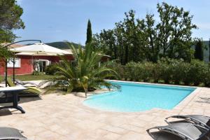 a swimming pool with chairs and an umbrella at La Lézardière in Bargemon
