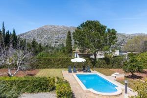 una piscina con sillas y sombrilla en Villa La Palmera By homevillas360, en Pollensa