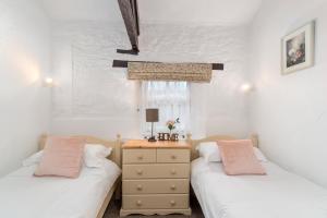 a bedroom with two beds and a dresser and a window at Rose Cottage in Paignton
