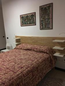 um quarto com uma cama e duas fotografias na parede em B&B Juighissa Leonora em Oristano