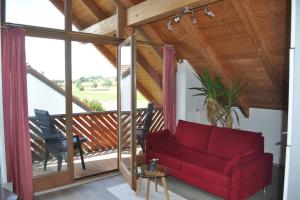 a living room with a red couch on a balcony at Ruhige Wohnung bei München, Fürstenfeldbruck, Dachau in Oberschweinbach