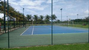 a tennis court with palm trees in the background at Condado Aldeia dos Reis in Mangaratiba
