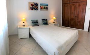 um quarto com uma grande cama branca e 2 candeeiros em Apartamento Praia Altura - Terraço BBQ - Wifi - AC - Garagem Fechada em Altura