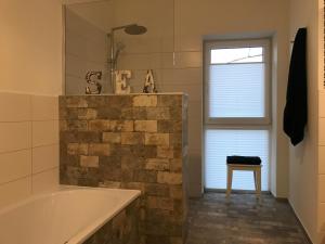 ein Badezimmer mit einer Badewanne und einem Hocker neben einem Fenster in der Unterkunft SEASIDE APARTMENTS - BEACHHOUSE SKY in Eckernförde