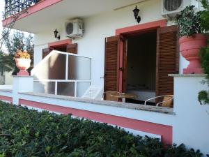 a white house with red accents and a patio at Tony studio & apartments in Laganas