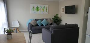 羅托魯阿的住宿－Rose Apartments Unit 6 Central Rotorua-Accommodation & Spa，客厅配有沙发和桌子