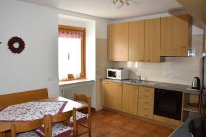 a kitchen with a table and a dining room at Appartamenti Osti Sansoni Mariarosa in Andalo