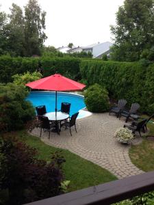 - une table avec un parasol rouge à côté de la piscine dans l'établissement Gite Les P'tits Pommiers, à Shawinigan