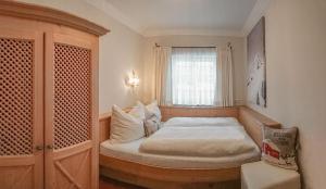 małą sypialnię z łóżkiem z oknem w obiekcie Appartement Erwin & Eleonore Hüttl w mieście Neukirchen am Großvenediger