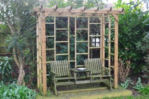 a wooden gazebo with two chairs and a table at Sunnycroft in Sutton on Sea