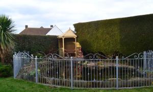 a fence in front of a hedge with a gazebo at Sunnycroft in Sutton on Sea