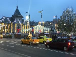 een drukke straat met auto's voor een gebouw met kerstverlichting bij Vintage Apartament Ultracentral in Craiova