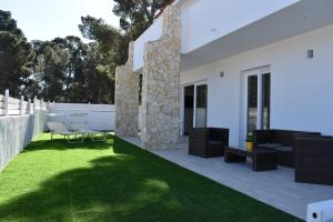 una casa bianca con un cortile con erba verde di Case Vacanze "Bianco Mare" a Porto Pino
