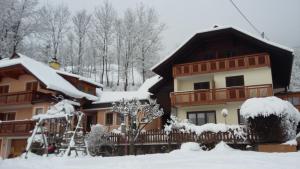 ein schneebedecktes Haus mit Bäumen im Hintergrund in der Unterkunft Müllnerhaus in Millstatt