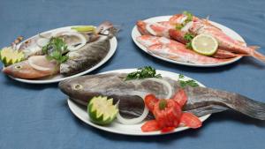 three plates of fish and vegetables on a table at Tylos Beach Hotel in Kato Pyrgos