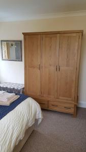 a bedroom with a bed and a wooden cabinet at Sunnycroft in Sutton on Sea