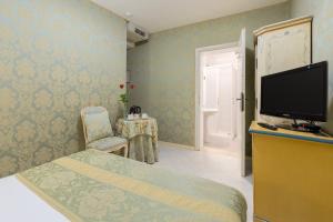 a bedroom with a tv and a bed and a chair at Hotel San Giorgio in Venice