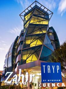 un grand bâtiment en verre avec un panneau devant lui dans l'établissement TRYP by Wyndham Cuenca Zahir, à Cuenca