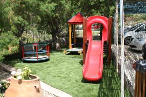 um parque infantil com um escorrega vermelho e um baloiço em Agios Pavlos Hotel em Agios Pavlos