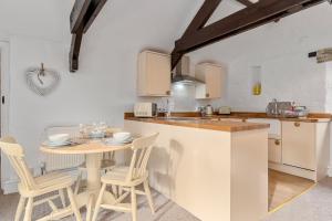 eine Küche mit einem Tisch, Stühlen und einer Theke in der Unterkunft Jasmine Cottage in Paignton