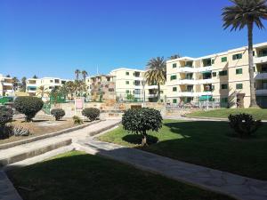 einen Park vor einem Gebäude mit einer Palme in der Unterkunft HUELLA CANARIA Complejo LAS OLAS in Playa del Ingles