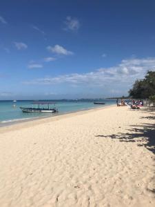 a beach with people and a boat in the water at Seascape Apartments in Negril