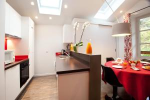 a kitchen with a table with a red counter top at Studio La Savoyarde - Vision Luxe in Menthon-Saint-Bernard