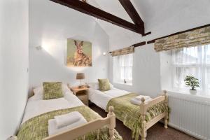 two beds in a room with white walls and windows at Mill Cottage in Paignton