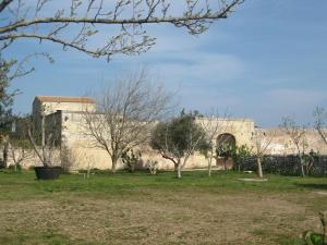 un bâtiment dans un parc avec des arbres au premier plan dans l'établissement Masseria Copertini, à Vernole